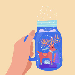 hand holding mason jar with winter landscape and deer