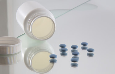 blue coated tablets in front of opened white plastic bottle