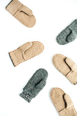 Grey and beige craft warm winter mittens on white background. Aesthetic minimalist DIY concept. Flat lay, top view fashion pattern