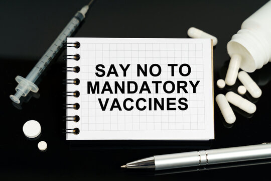 On the black surface are pills, a syringe and a notebook with the inscription - Say no to mandatory vaccines