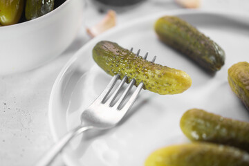 Pickled gherkin on a fork, salted cucumber close up