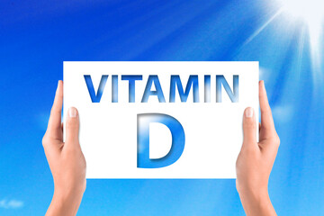 Vitamin D concept with hands holding the white paper on blue sky background
