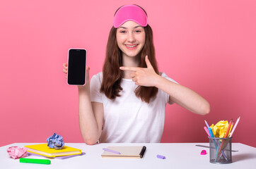 Fototapeta Cheerful nice girl holding smart phone in hand showing blank screen isolated on pink background distance online education concept young blogger shoots tik tok youtube content on the phone obraz