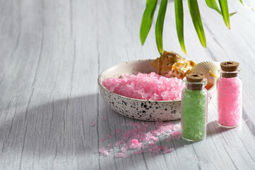 Cosmetic sea salt of pink and green color for spa treatments on a light background, selective focus
