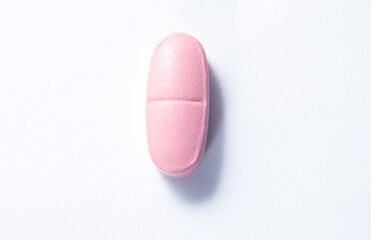 Pink pill on a white background close-up