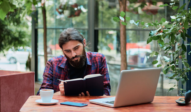 Hipster guy enjoying free time and planning to do list in notebook