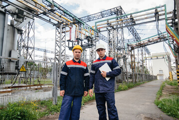 Two specialist electrical substation engineers inspect modern high-voltage equipment. Energy. Industry