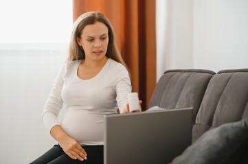 Online prenatal consultation. Pregnant woman having video call with doctor on laptop from home. Unrecognizable future mother communicating with therapist, consulting about health problem