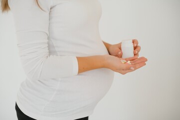 belly of pregnant woman and vitamin pills in the hand