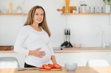 pregnant woman slicing vegetables at home in the kitchen