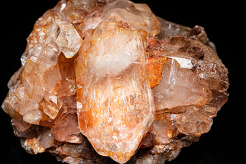 Mineral stone Quartz cluster isolated, selective focus on black table. Natural pure brown shiny rock found in the river. Macro close up of glassy brown orange raw Quartz crystal. Home decoration.