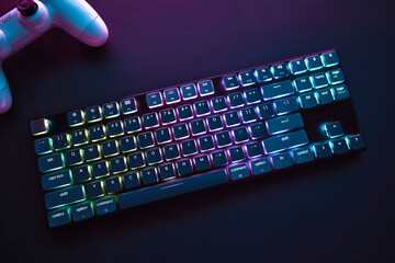 Top down view of color backlighted gaming accessories laying on dark desk.