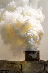 The fuming smoke grenade on a destroyed brick wall during tactical training. Used as a signaling...