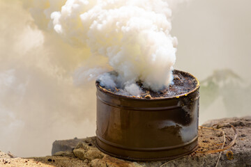 Fototapeta na wymiar The fuming smoke grenade on a destroyed brick wall during tactical training. Used as a signaling device, target or landing zone marking device, or as a screening device for military unit movements