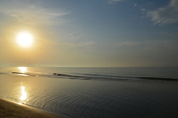 sunrise over a calm sea in good weather. sandy beach and small waves.