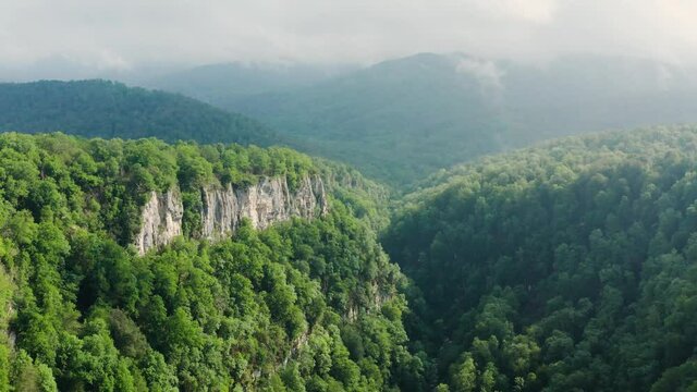 Caucasus Mountains, Akhun mountain range. Navalishinsky Canyon (White rocks). The valley of the Bolshaya Khosta River in fog. Aerial view.