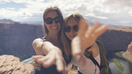 Happy people celebrating cheering in Grand Canyon. Young multiethnic couple on hiking travel...