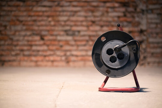 Electric Power Extension Cord Reel On The Floor Of Construction Site Close Up.