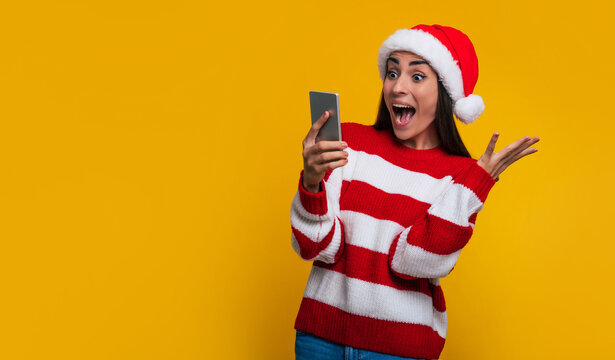 Excited beautiful shouting woman with smart phone in hands due to she win some present in Christmas time
