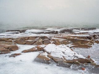 Freezing winter shoreline with rocks and icy waves.