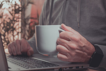 Freelancer is drinking coffee and working from home on laptop computer