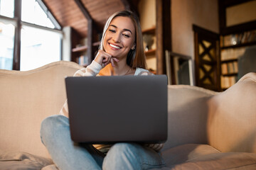 Fototapeta na wymiar Smiling woman working on laptop at home