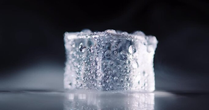 Closeup ice cubes with smoke rotating on dark background.