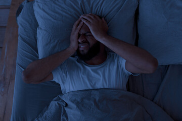 Black man suffering from headache or migraine at night