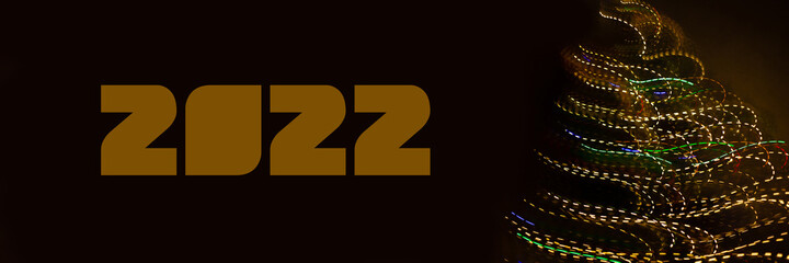 Abstract background of Christmas lights with long exposure. Colorful 2022 number on black background
