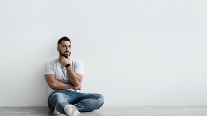 Sad shocked unhappy pensive handsome guy sit on floor, think and suffering from depression