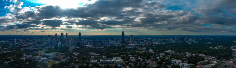 Fototapeta na wymiar a stunning aerial panoramic shot of the cityscape at sunset with skyscrapers surrounded by powerful clouds and lush green trees in Atlanta Georgia USA