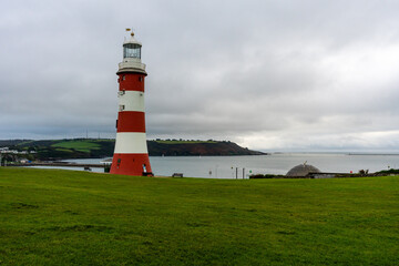 Fototapeta na wymiar Smeaton's Tower Lighthouse overlooking the harbour and breakwater on an overcast autumn / winter afternoon. Copy space.