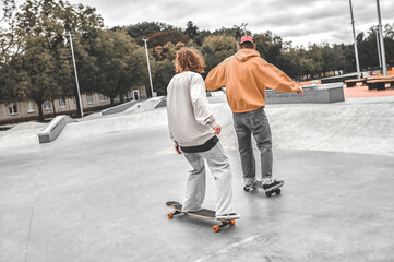 Back view of guy and girl sliding on skateboards