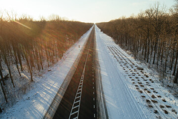 Obraz premium Construction of a new asphalt road in a winter forest