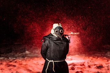 Medieval plague doctor stands in the bloody snowfall. Medieval Europe. Halloween.