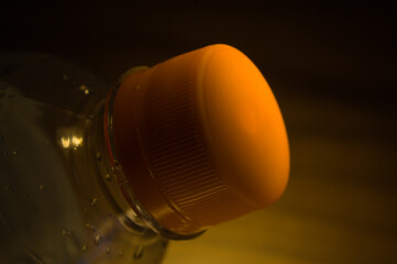 Transparent water bottle with orange cap.