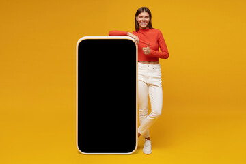 Young woman standing and showing blank screen of huge phone, mockup for your app