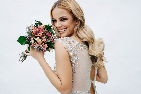 Happy bride with bouquet near wall