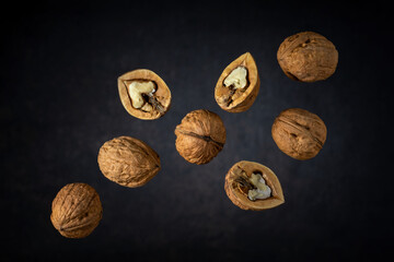 flying dried walnuts against a dark gray backdrop with a light spot