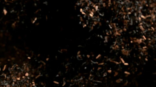 Super slow motion of dry tea leaves flying in the air on a black background, 1000 fps.