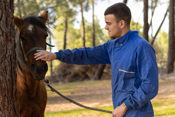 portrait of a young farmer petting his horse