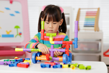 young girl playing water pipe construction toy at home