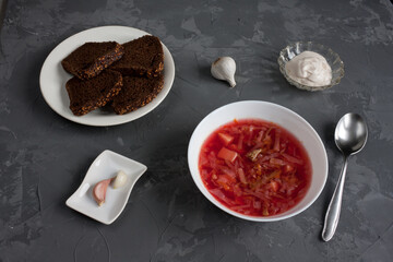 National Slavic dish is borsch. Traditional main first dish of Ukrainian cuisine is red borsch with rye bread. Served with sour cream and garlic. On table is gray.