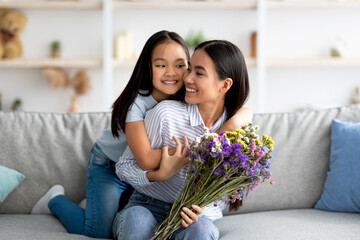 I love you, mommy. Excited asian girl greeting mom with birthday or mother's day, giving her flowers and embracing