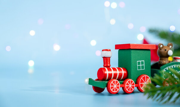Colorful green Christmas train with red wheels and different toys on it on blue background for design. Happy New Year, Merry Christmas or winter holidays coming soon.