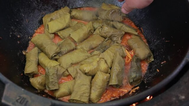 People cook dolma food.
Grape leaves stuffed with minced meat.