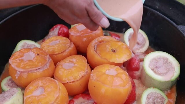 People hands are preparing food. Peppers, tomatoes, zucchini and grape leaves stuffed with minced meat.
