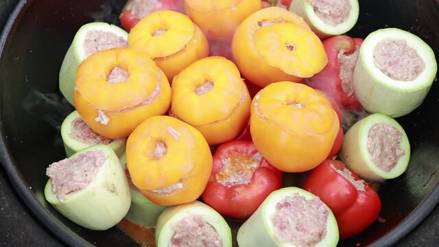 People hands are preparing food. Peppers, tomatoes, zucchini and grape leaves stuffed with minced meat.