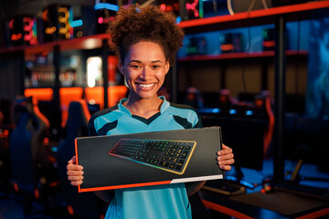 Happy African female cybersports gamer won multiplayer PC video game on esports tournament and got trophy in computer club