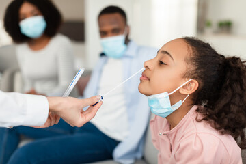 Nurse taking nasal PCR test sample from black teen girl